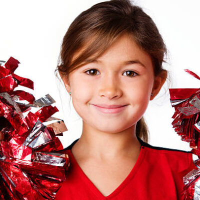Cute adorable little cheerleader holding pompoms